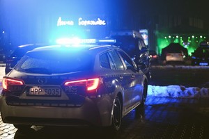 Zdjęcie przedstawia radiowóz policyjny z włączonymi światłami uprzywilejowania koloru niebieskiego w nocy