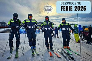 Zdjęcie przedstawia po czterech policjantów na nartach stojących na stoku. W prawym górnym rogu czarny napis na niebieskim tle : Bezpieczne ferie 2026.