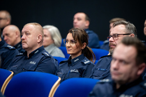Kolorowe zdjęcie umundurowanych policjantów siedzących na widowni rotundy.