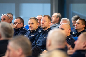 Kolorowe zdjęcie umundurowanych policjantów siedzących na widowni rotundy.