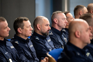 Kolorowe zdjęcie umundurowanych policjantów siedzących na widowni rotundy.