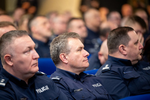 Kolorowe zdjęcie umundurowanych policjantów siedzących na widowni rotundy.