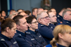 Kolorowe zdjęcie umundurowanych policjantów siedzących na widowni rotundy.