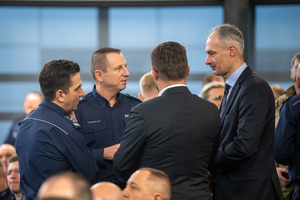 Kolorowe zdjęcie umundurowanych policjantów stojących z zaproszonymi gośćmi.