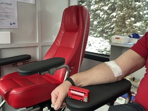 Na zdjęciu czerwony fotel oraz zbliżenie na rękę mężczyzny po pobraniu krwi