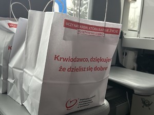 Zbliżenie na trzy białe papierowe torby z napisami : Łączy nas krew, która ratuje życie, bo tętni w nas dobro. Krwiodawco, dziękujemy, że dzielisz się dobrem. Na dole logo i napis: Regionalne Centrum Krwiodawstwa i krwiolecznictwa w Katowicach