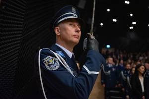 Zbliżenie na policjanta trzymającego w zgiętej ręce szablę