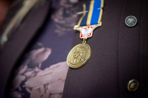 Zbliżenie na medal w kolorze złotym z wizerunkiem policjantki i napisem; siła, która inspiruje