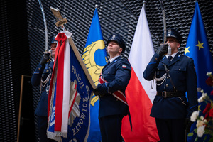 Na zdjęciu trzej policjanci z pochylonym sztandarem Komendy Wojewódzkiej policji w Katowicach