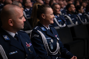 Na zdjęciu policjanci i policjantka siedzący na sali w trakcie uroczystości
