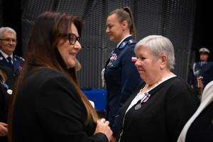 Na zdjęciu kobieta i policjantka z medalami oraz kobieta stojąca przed nimi