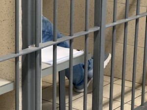 Zbliżenie na nogi zatrzymanego siedzącego w celi