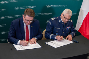 Na zdjęciu Komendant Wojewódzki z mężczyzna podpisujący porozumienie.