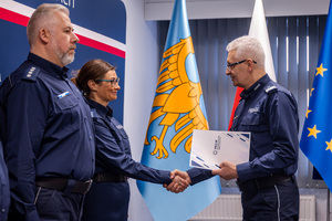 Zdjęcie przedstawia policjanta i policjantkę oraz stojącego na przeciw nich Komendanta Wojewódzkiego Policji, podającego rękę policjantce