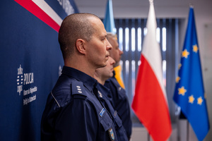 Grafika przedstawia trzech policjantów stojących bokiem na tle flagi Polski oraz Unii Europejskiej