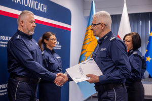 Zdjęcie przedstawia policjanta i policjantkę oraz stojącego na przeciw nich Komendanta Wojewódzkiego Policji podającego rękę policjantowi