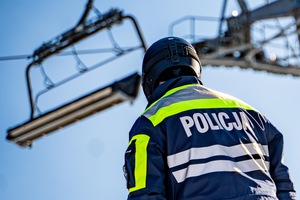 Na zdjęciu mężczyzna tyłem w kasku i kurtce z napisem Policja na stoku