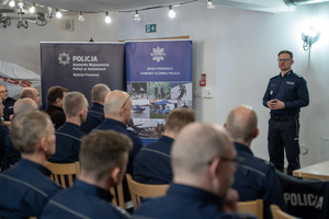 Policjant prowadzi wystąpienie przed grupą funkcjonariuszy podczas spotkania