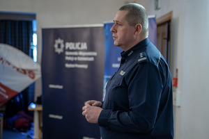 Na zdjęciu policjant stojący bokiem