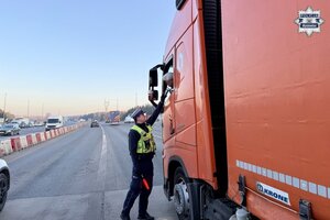 Policjant z urządzeniem do badania trzeźwości wykonuje czynności służbowe z kierowcą tira.