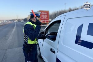 Policjant sprawdzający trzeźwość kierowcy białego dostawczaka.