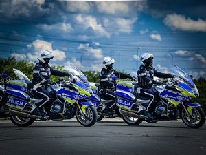 Zdjęcie przedstawia trzech jadących policjantów umundurowanych na motocyklach marki BMW.