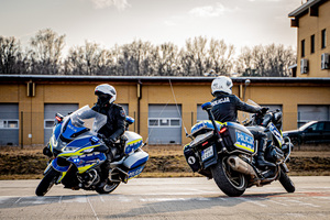 Zdjęcie mijających się dwóch motocyklistów na motocyklach służbowym marki BMW.