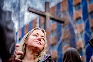 Na kolorowym zdjęciu kobieta na tle krzyża