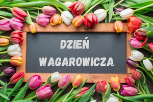 Na ciemnej tabliczce napis Dzień Wagarowicza. Dookoła tabliczki widzimy jeszcze ozdobne tulipany.
