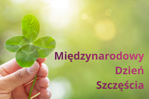 na zdjęciu widzimy czterolistną koniczynę trzymaną w ręku i napis obok Międzynarodowy Dzień Szczęścia.