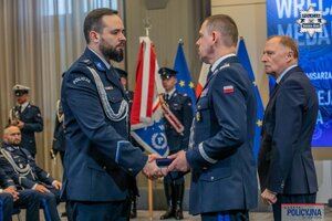 Komendant Główny Policji wręczający kolejny medal zasłużonemu policjantowi, w tle widzimy siedzących zaproszonych gości na galę.