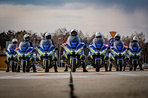 Policjanci na motocyklach w rzędzie stoją przodem do nas