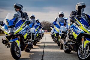 Policjanci jadący na motocyklach w dwóch rzędach szykują się do manewru skrętu