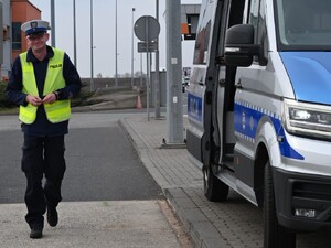 umundurowany policjant ruchu drogowego stojący przy oznakowanym radiowozie