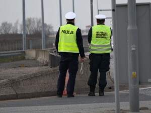 na zdjęciu widizmy stojących przy autostradzie policjanta oraz funkcjonariusza inspekcji transportu drogowego