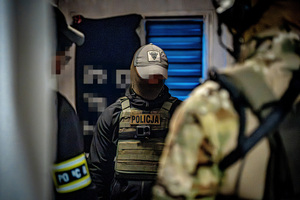 na zdjęciu widzimy trzech policjantów rozmawiających ze sobą w małym pomieszczeniu.