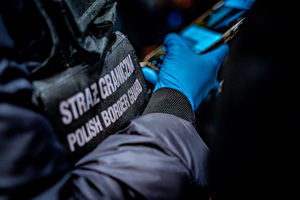Na zdjęciu widzimy funkcjonariusza Straży Granicznej korzystającego z telefonu komórkowego.