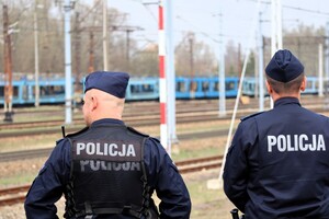 na zdjęciu widzimy dwóch policjantów stojących tyłem na torowisku.