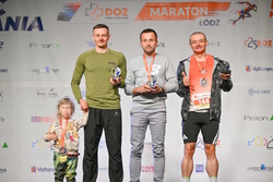 na zdjęciu trzech mężczyzn na podium, w tym jeden trzyma dziecko za rękę