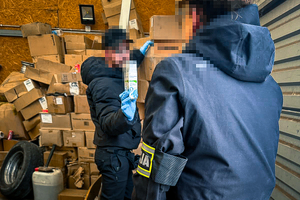 na zdjęciu widoczni są funkcjonariusze policji na tle dużej ilości kartonów