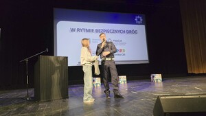 na zdjęciu umundurowany policjant daje nagrodę dziewczynie - uczestniczce wykładu