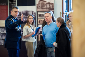 na zdjęciu umundurowany policjant wskazuje ręką kierunek osobom cywilnym