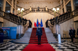 na zdjęciu dowódca uroczystości stoi na baczność na czerwonym dywanie, a z tyłu za nimi po bokach stoją policjanci umundurowani