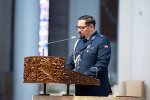 zdjęcie przedstawia funkcjonariusza policji w mundurze galowym stojącym przed amboną kościelną