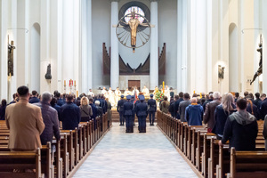 zdjęcie przedstawia wnętrze kościoła, w ławach stoją wierni, na środku funkcjonariusze w mundurach galowych,  na ołtarzu księża odprawiają mszę
