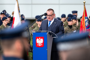 na zdjęciu uczestnik uroczystości przemawiający przed mównicą z godłem Polski