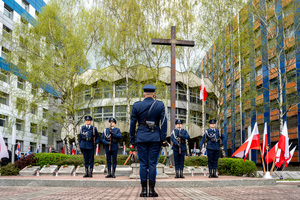 na zdjęciu obchody uroczystości, funkcjonariusze policji w umundurowaniu galowym na tle krzyża oraz Komendy Wojewódzkiej Policji w Katowicach