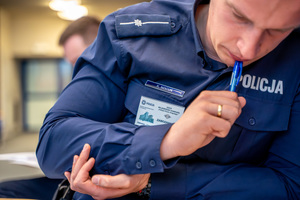 na zdjęciu pochylający się nad testem funkcjonariusz policji biorący udział w konkursie