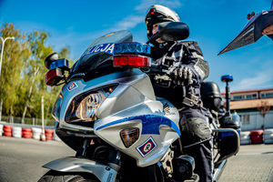 zdjęcie przedstawia policjanta na motocyklu służbowym podczas jednej z konkurencji na torze przeszkód
