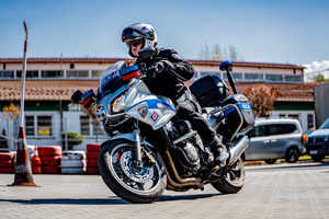 zdjęcie przedstawia policjanta na motocyklu służbowym podczas jednej z konkurencji na torze przeszkód